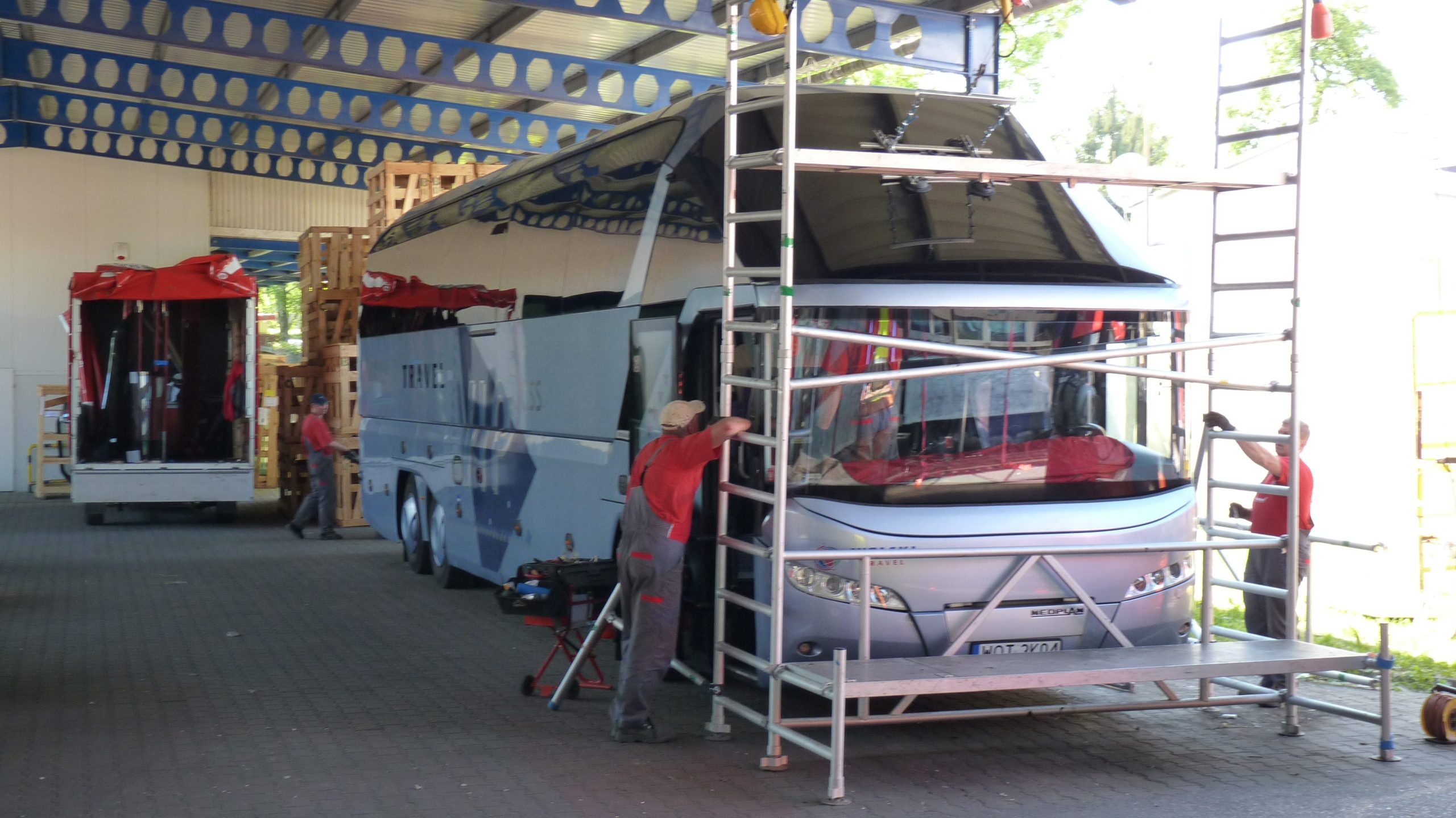 Pracownicy sprzątają niebieski autobus turystyczny.